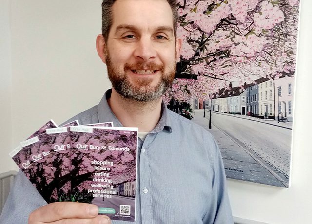 Local artist Tom Crittenden holds Our Bury Town map in front of his cherry blossom painting