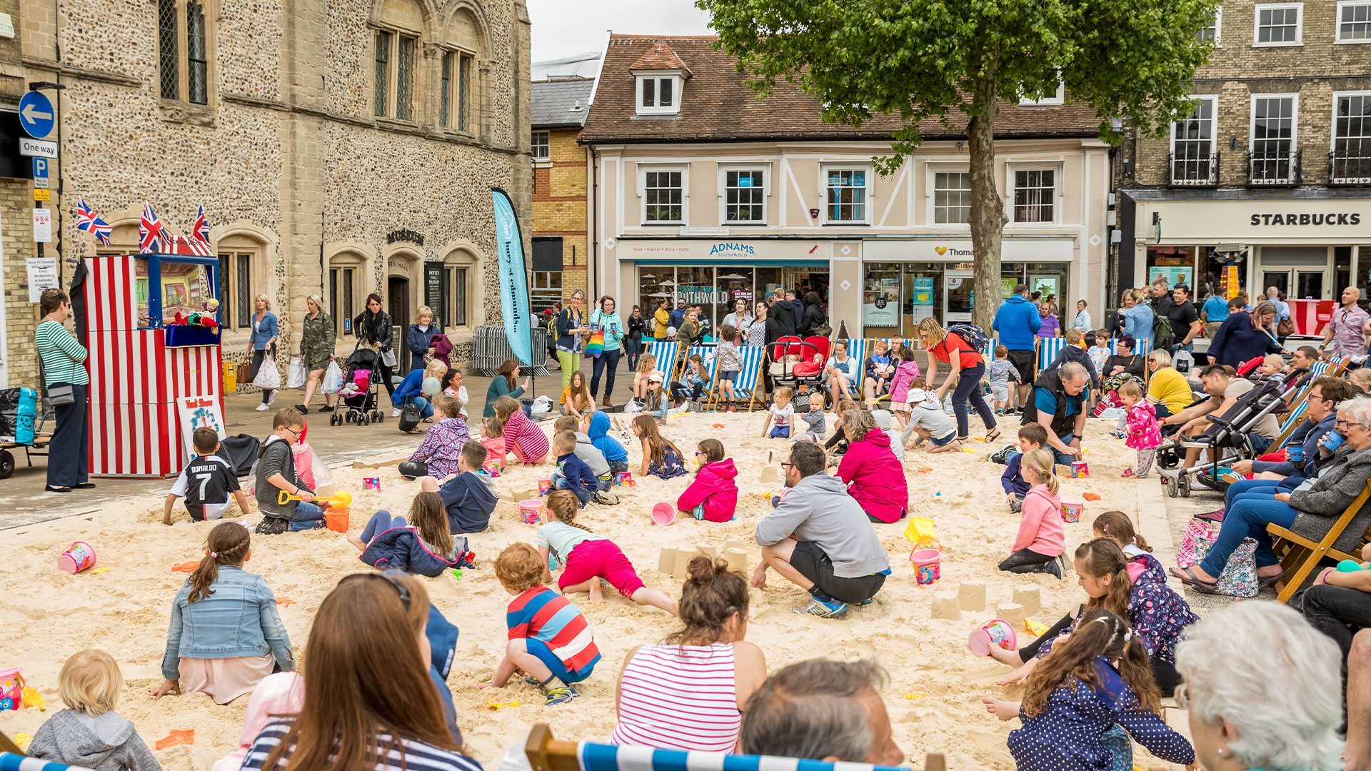 Children sat on sand watching Punch and Judy